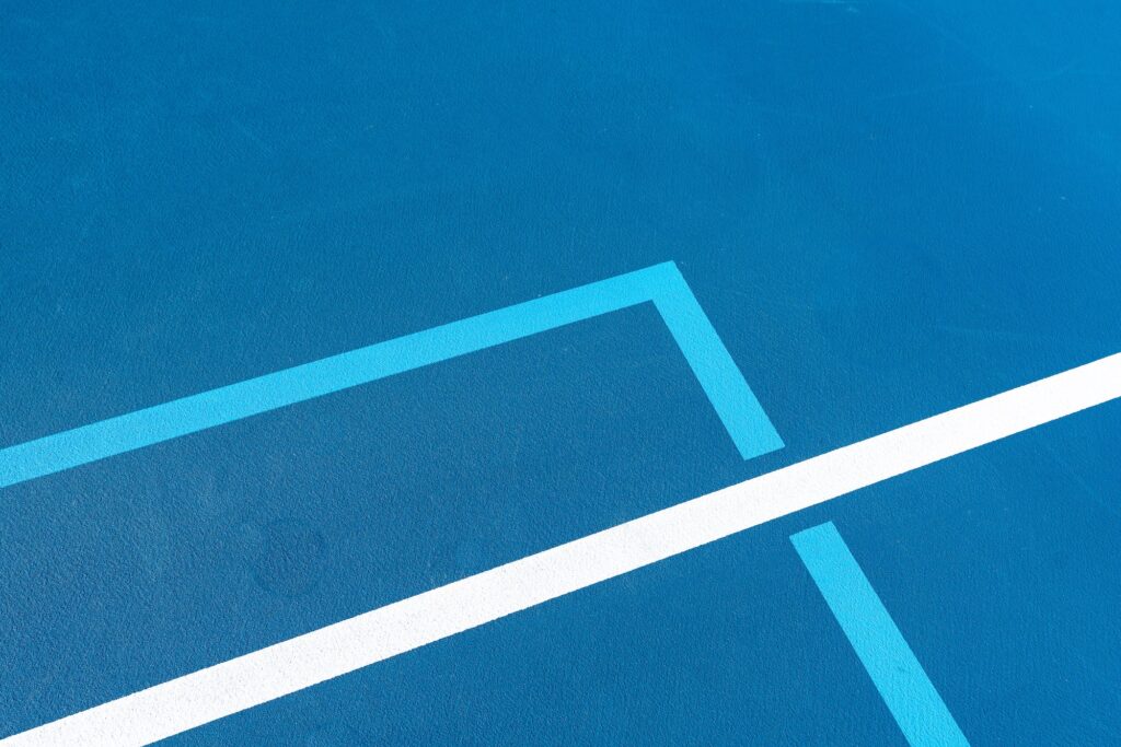 Closeup of the intersection of blue tennis courts with white lines and light blue pickleball lines